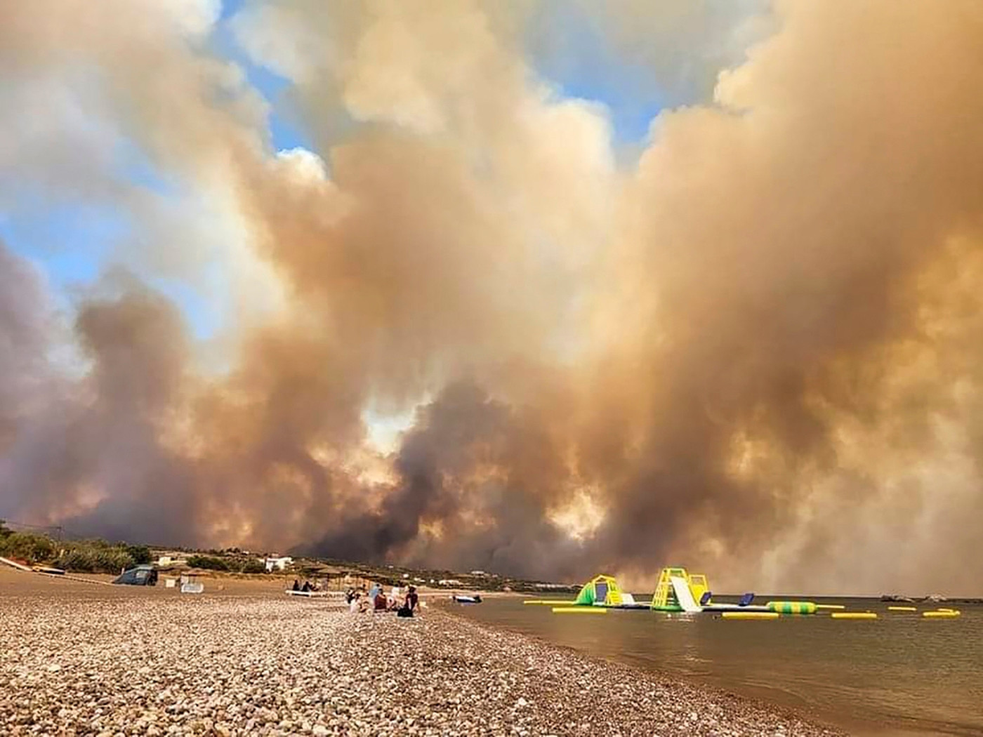 Während der Evakuierung: Am Strand sind Rauchwolken eines Waldbrandes zu sehen. 