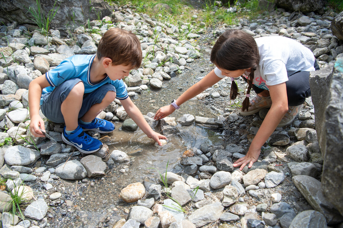 Wasser bändigen leicht gemacht: Lou und Dea stauen das Wasser mit Steinen.